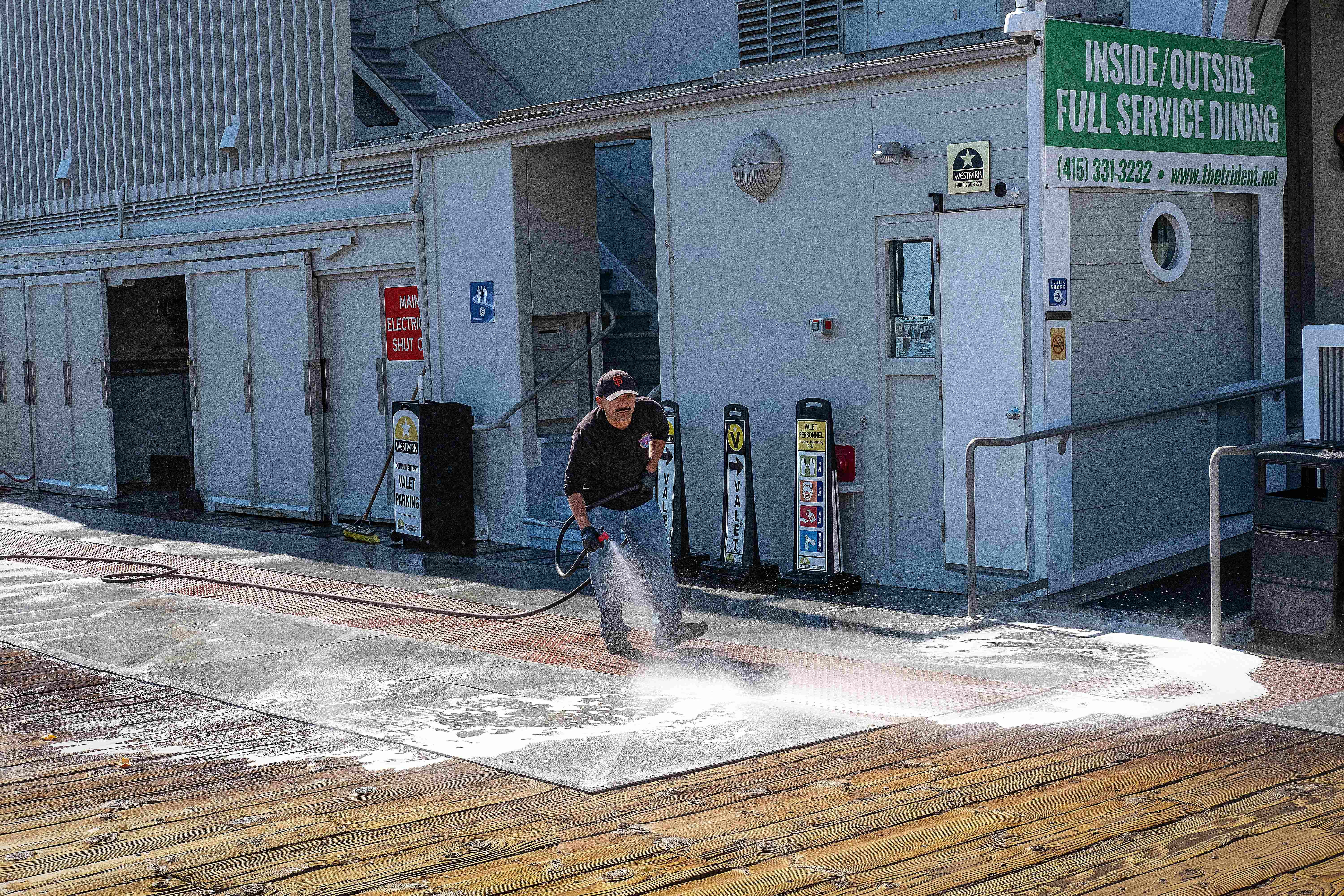 Commercial pressure washing of wooden deck and pier surface - industrial cleaning removes algae, dirt, and weathering from outdoor commercial spaces